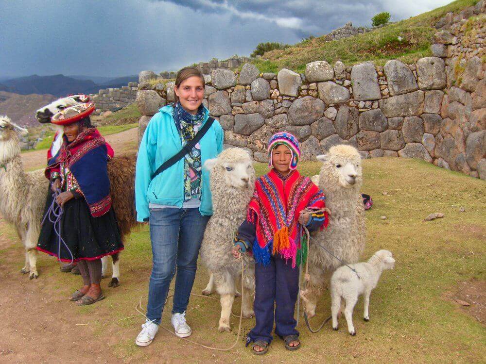 Mädchen mit peruanischem Jungen in traditioneller Andentracht und zwei Alpakas. 